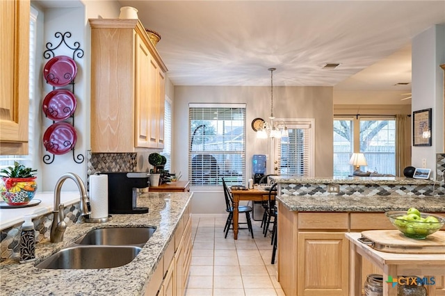 kitchen with light brown cabinetry, sink, and backsplash