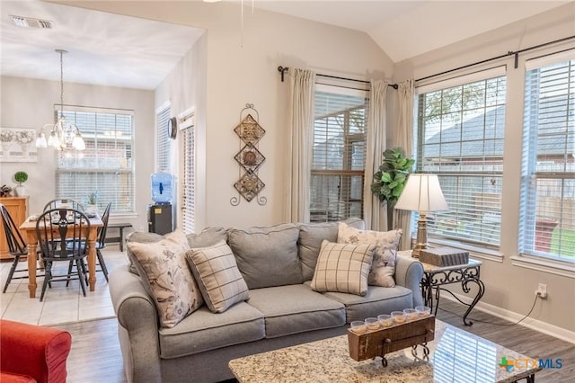 living room featuring an inviting chandelier, vaulted ceiling, and light hardwood / wood-style floors