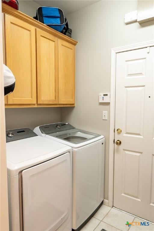 clothes washing area featuring cabinets, light tile patterned floors, and washer and dryer