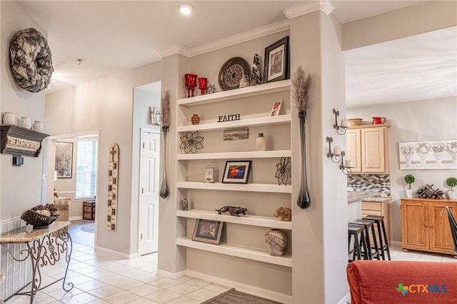 hallway featuring ornamental molding and light tile patterned floors