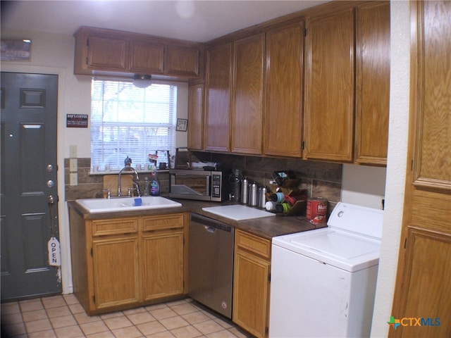 kitchen with decorative backsplash, stainless steel appliances, sink, washer / clothes dryer, and light tile patterned flooring