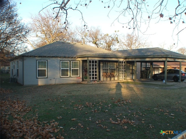 rear view of house featuring central AC, a yard, and a carport