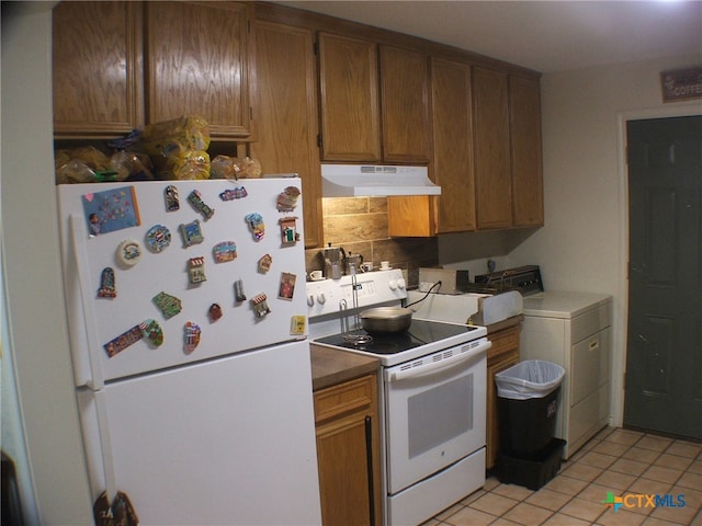 kitchen with light tile patterned flooring, white appliances, backsplash, and washer / clothes dryer