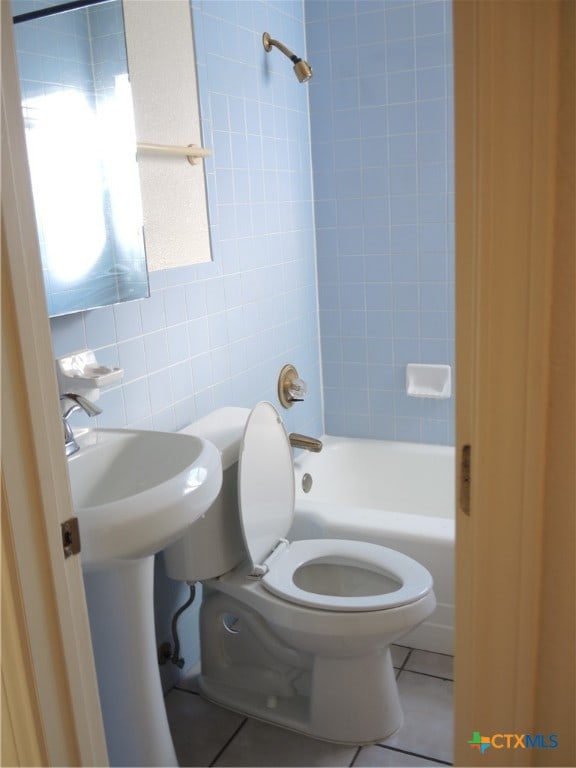 bathroom featuring tile patterned flooring, toilet, tile walls, and tub / shower combination