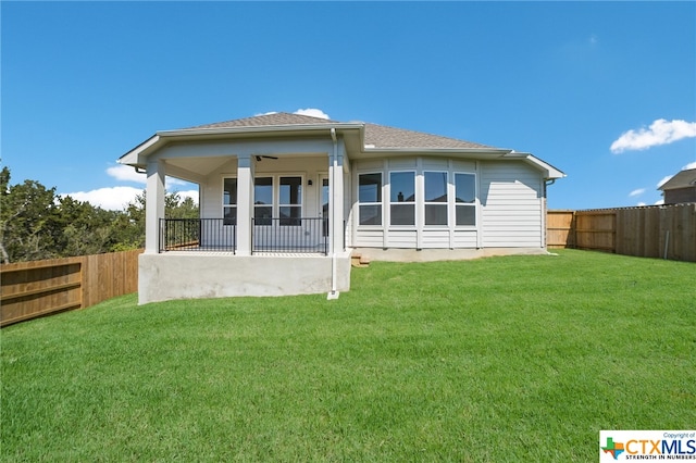 rear view of property featuring a porch, a yard, and ceiling fan