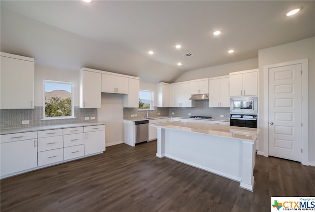 kitchen with a wealth of natural light, white cabinetry, appliances with stainless steel finishes, and lofted ceiling