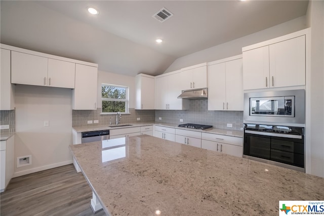 kitchen with stainless steel appliances, light stone countertops, vaulted ceiling, light hardwood / wood-style floors, and white cabinets