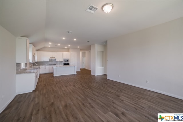 kitchen with dark wood-type flooring, white cabinetry, appliances with stainless steel finishes, and a center island