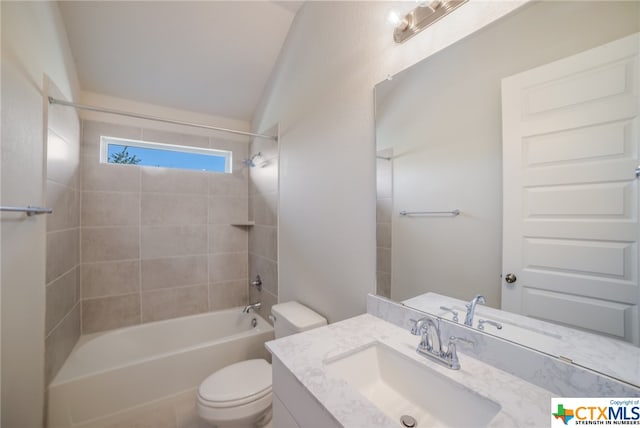 full bathroom with vanity, tiled shower / bath, toilet, and vaulted ceiling