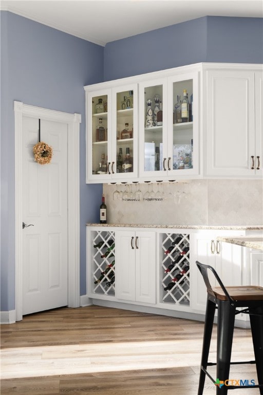 bar with light hardwood / wood-style floors and white cabinetry