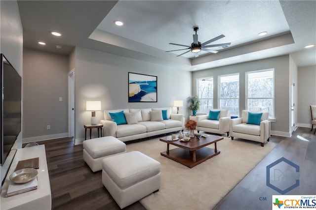 living room featuring a textured ceiling, a tray ceiling, hardwood / wood-style flooring, and ceiling fan