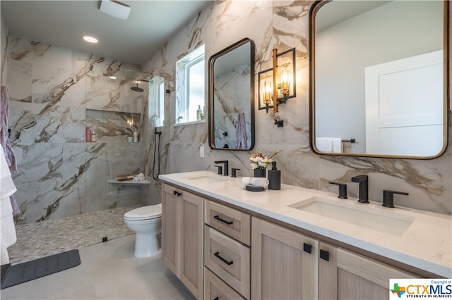 bathroom with a tile shower, toilet, decorative backsplash, vanity, and tile walls