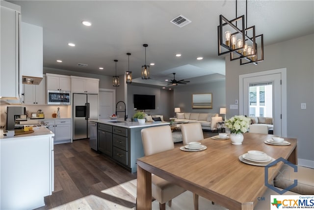 dining room with ceiling fan with notable chandelier, dark hardwood / wood-style floors, and sink