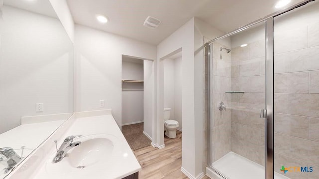 bathroom featuring walk in shower, vanity, toilet, and hardwood / wood-style flooring