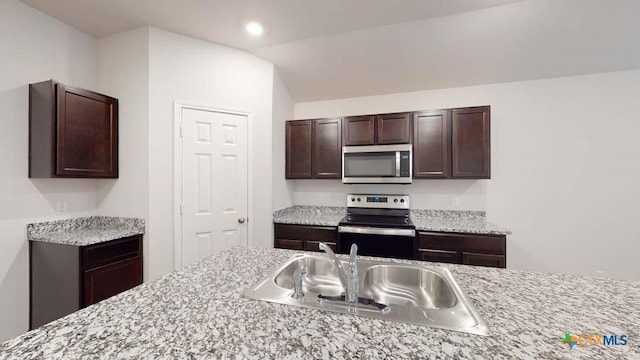 kitchen with dark brown cabinetry, sink, vaulted ceiling, and stainless steel appliances