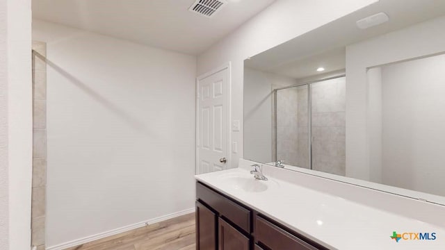 bathroom featuring vanity, wood-type flooring, and a shower with door