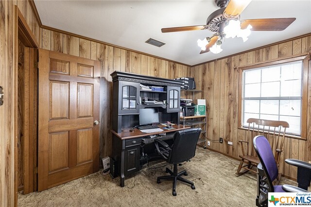 office area featuring crown molding, wooden walls, light carpet, and ceiling fan