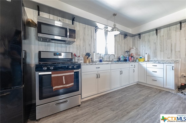 kitchen with white cabinetry, light stone counters, decorative light fixtures, and appliances with stainless steel finishes