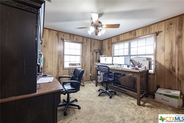 carpeted office with plenty of natural light, wooden walls, and ceiling fan