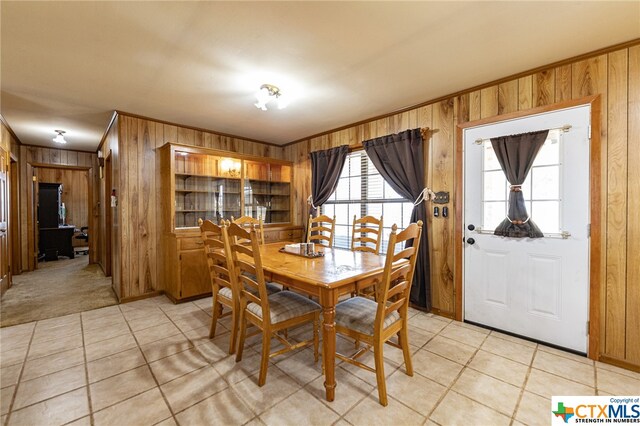 tiled dining space with ornamental molding and wood walls