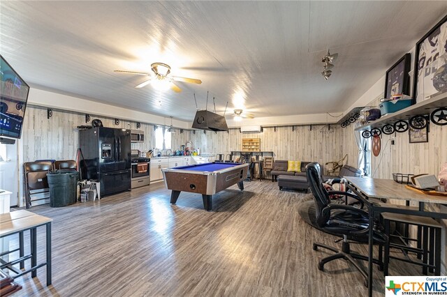 rec room with billiards, ceiling fan, hardwood / wood-style floors, wooden walls, and an AC wall unit