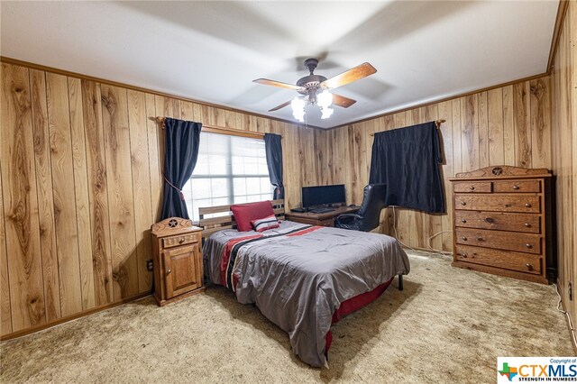 carpeted bedroom featuring ceiling fan and wood walls