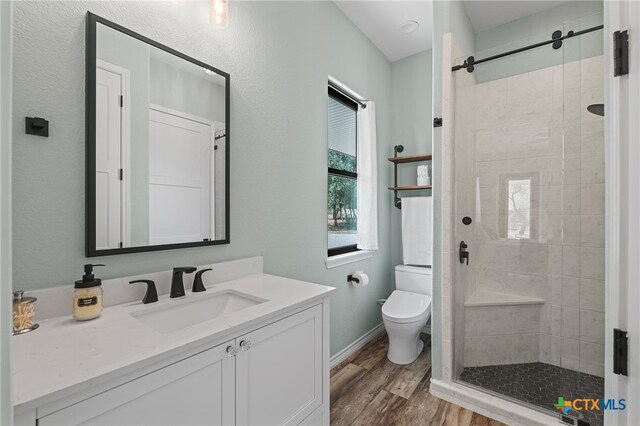 bathroom featuring walk in shower, wood-type flooring, vanity, and toilet