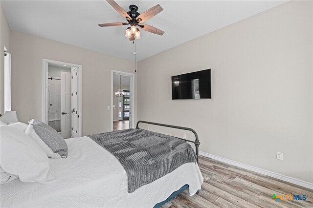 bedroom with light hardwood / wood-style floors, ceiling fan with notable chandelier, and ensuite bathroom