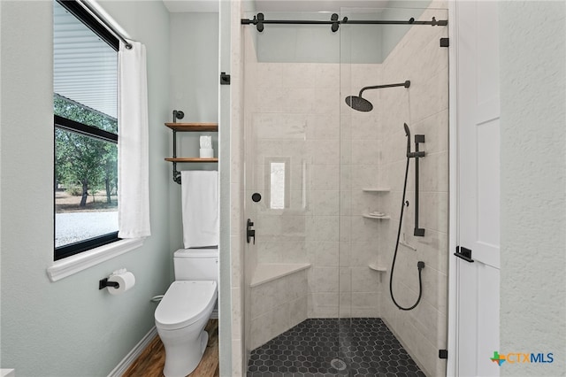 bathroom featuring hardwood / wood-style floors, toilet, and a shower with shower door