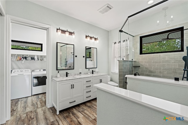 bathroom featuring hardwood / wood-style flooring, vanity, an enclosed shower, washing machine and clothes dryer, and toilet