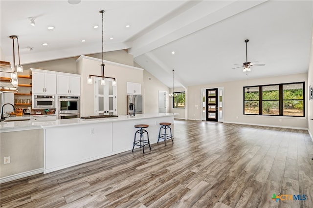 kitchen with light wood-type flooring, sink, vaulted ceiling with beams, and stainless steel appliances