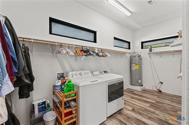 clothes washing area featuring light hardwood / wood-style floors, electric water heater, and washer and dryer