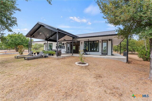 rear view of house featuring an outdoor fire pit, ceiling fan, a patio, and a lawn