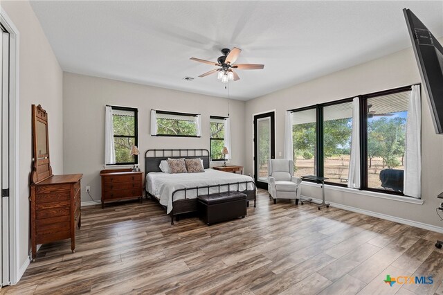 bedroom with hardwood / wood-style flooring, ceiling fan, and multiple windows