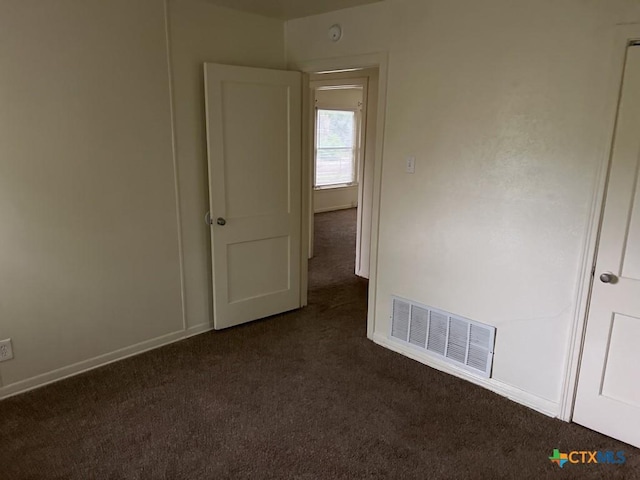 unfurnished room featuring visible vents, baseboards, and dark colored carpet