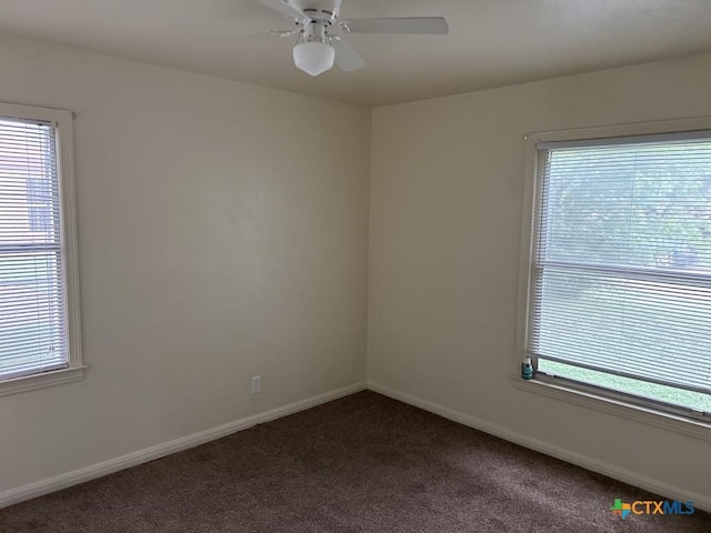 carpeted empty room featuring a wealth of natural light, baseboards, and a ceiling fan