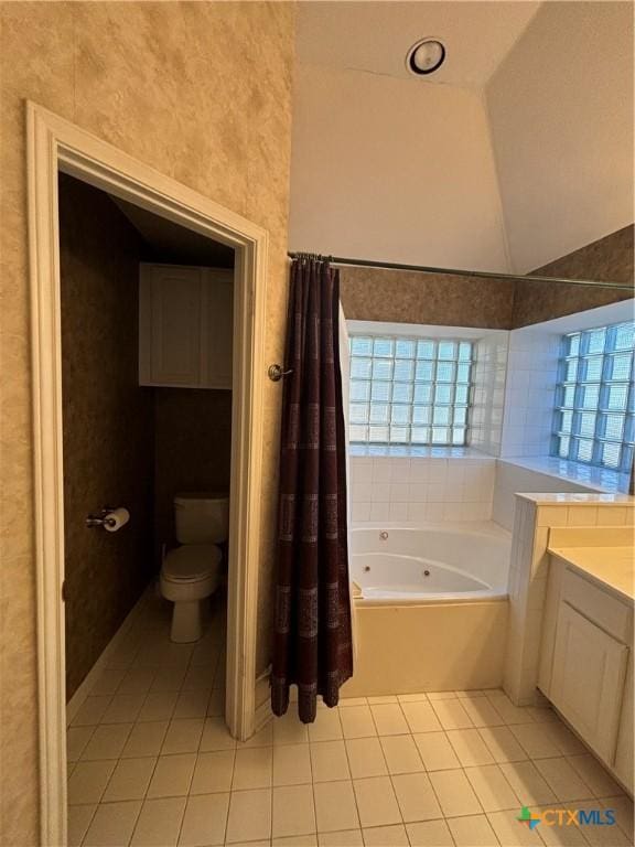 bathroom featuring tile patterned floors, vanity, lofted ceiling, toilet, and a tub