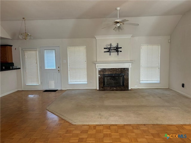 unfurnished living room featuring ceiling fan with notable chandelier, lofted ceiling, light parquet flooring, and a premium fireplace