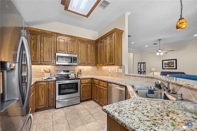 4105 Whispering Oaks, Temple, TX 76504 - kitchen featuring appliances with stainless steel finishes, brown cabinets, tasteful backsplash, ceiling fan, and hanging light fixtures