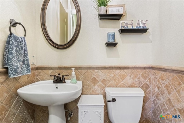 bathroom with toilet and a wainscoted wall