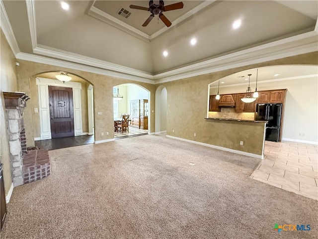 unfurnished living room with arched walkways, light colored carpet, crown molding, and visible vents