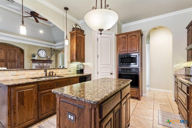 kitchen with ornamental molding, ceiling fan, black appliances, pendant lighting, and a center island