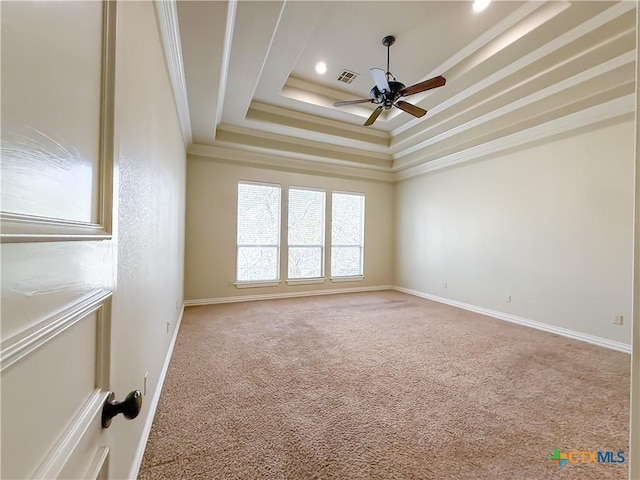 empty room with a tray ceiling, visible vents, ornamental molding, a ceiling fan, and carpet flooring