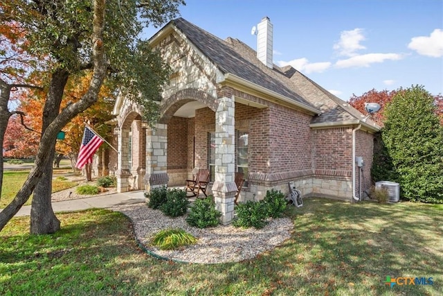 view of home's exterior with brick siding, a yard, a chimney, central air condition unit, and a shingled roof