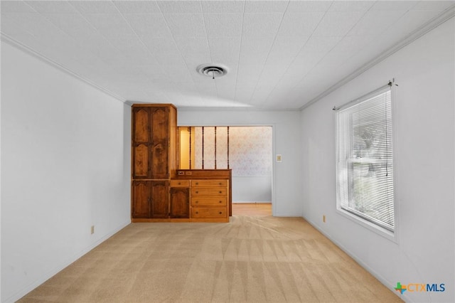 empty room with ornamental molding and light colored carpet