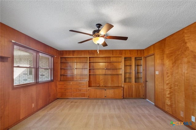 unfurnished living room with wooden walls and light colored carpet