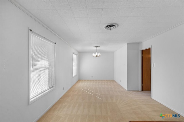 carpeted empty room featuring an inviting chandelier and ornamental molding