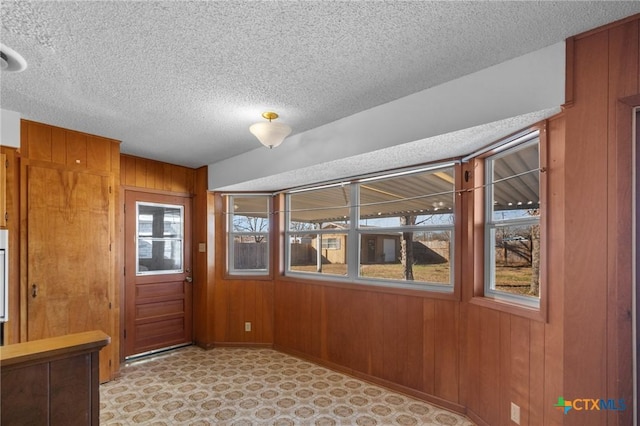 interior space featuring a textured ceiling and wood walls