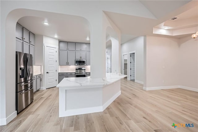 kitchen with tasteful backsplash, appliances with stainless steel finishes, gray cabinetry, and a center island