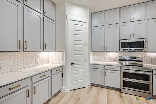 kitchen with backsplash, gray cabinets, and stainless steel appliances